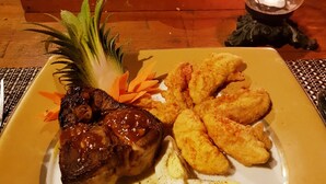 Un tavolo da pranzo imbandito con diverse portate, tra cui un piatto con carne, uova e cibi fritti, e diverse ciotole di zuppa.
