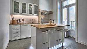 A modern kitchen with white cabinetry, a wooden countertop, and a large window.