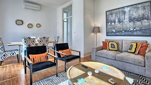 A living room with a sofa, two armchairs, a coffee table, and a painting on the wall.