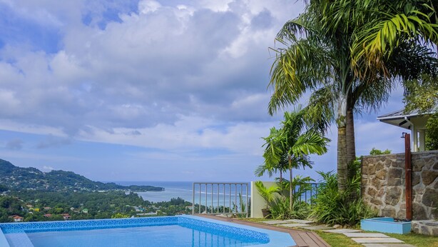 A swimming pool with a view of the sea and hills.