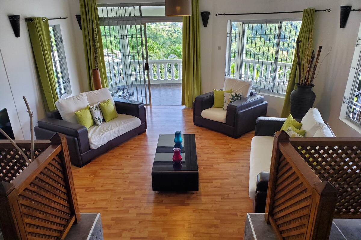 A living room with two sofas, a coffee table, and a view of a balcony with a railing.