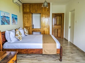 A bedroom with a wooden bed, a nightstand, a dresser, and a wardrobe. There are two paintings on the wall.
