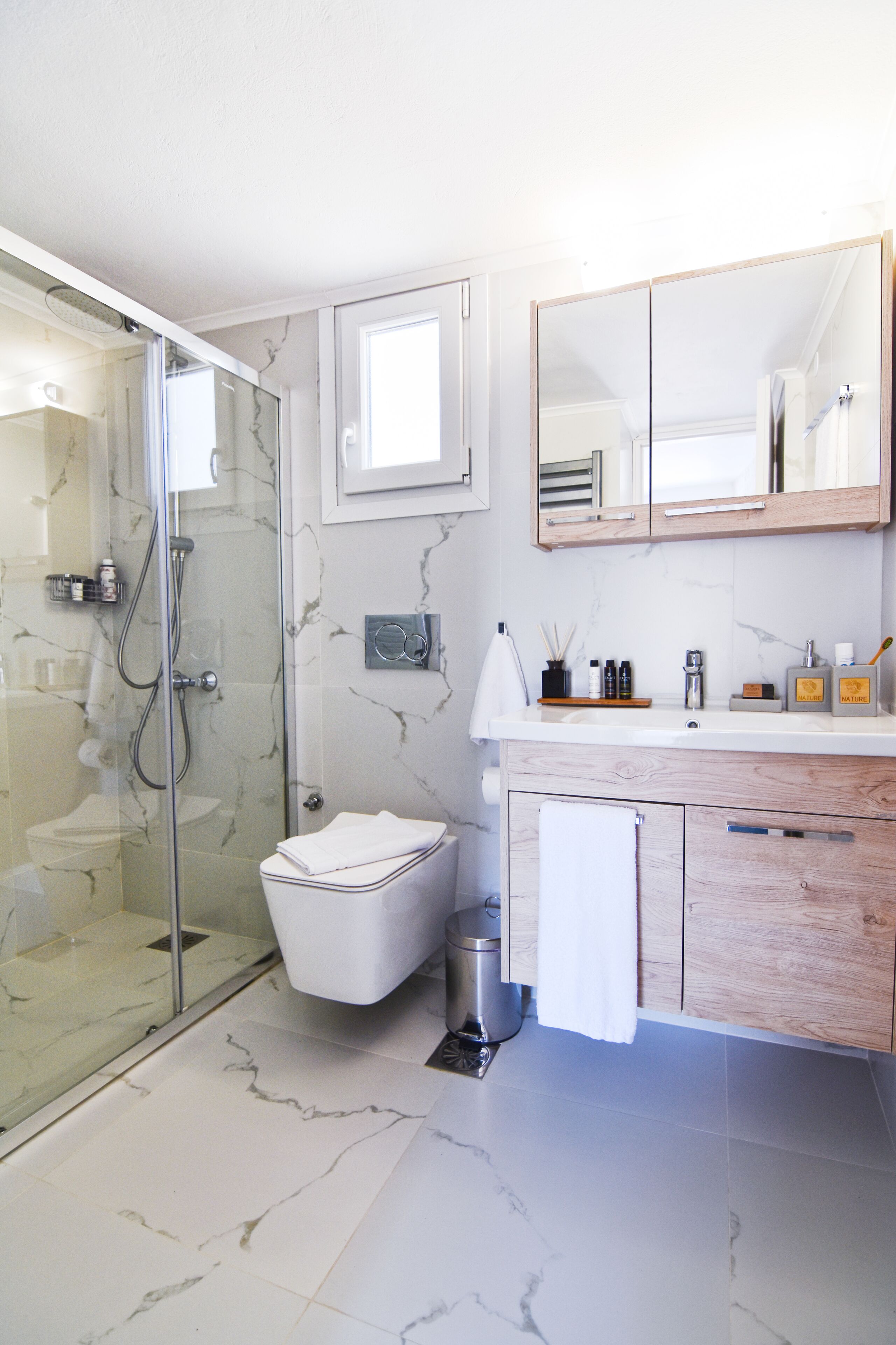 Un bagno moderno con cabina doccia in vetro, un water e un lavabo con specchio e spazio contenitore.