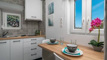 A modern kitchen with white cabinets, a wooden countertop, and a window with a view of the sky.