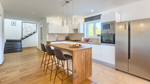 Una cocina moderna con armarios blancos, una isla de madera y electrodomésticos de acero inoxidable.
