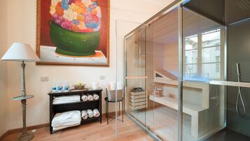 Un bagno moderno con cabina doccia in vetro, pavimento in legno, porta asciugamani e un quadro raffigurante un vivace bouquet di fiori.
