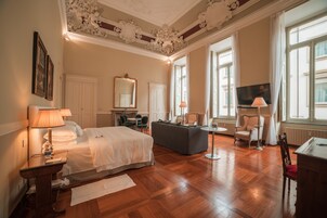 Una habitación de hotel con una cama grande, un sofá, un televisor y un escritorio.