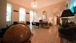 A spacious room with a globe, a chandelier, a television, and a dining area. - Royal Palace Luxury Suites & Hotel (Turin)