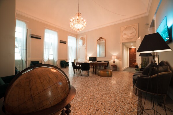 A spacious room with a globe, a chandelier, a television, and a dining area. - Royal Palace Luxury Suites & Hotel (Turin)