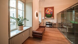 A modern interior with a wooden bench, a potted plant, a large painting, and a glass partition. - Royal Palace Luxury Suites & Hotel (Turin)