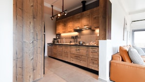 A modern kitchen with wooden cabinets, a built-in oven, and a countertop with various appliances. - Nino's Country House (Milos)