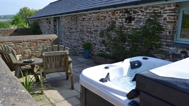 A stone building with a hot tub in front. There is a wooden table and chairs outside. - Converted barn, with hot tub near to North Devon's beaches (Barnstaple)