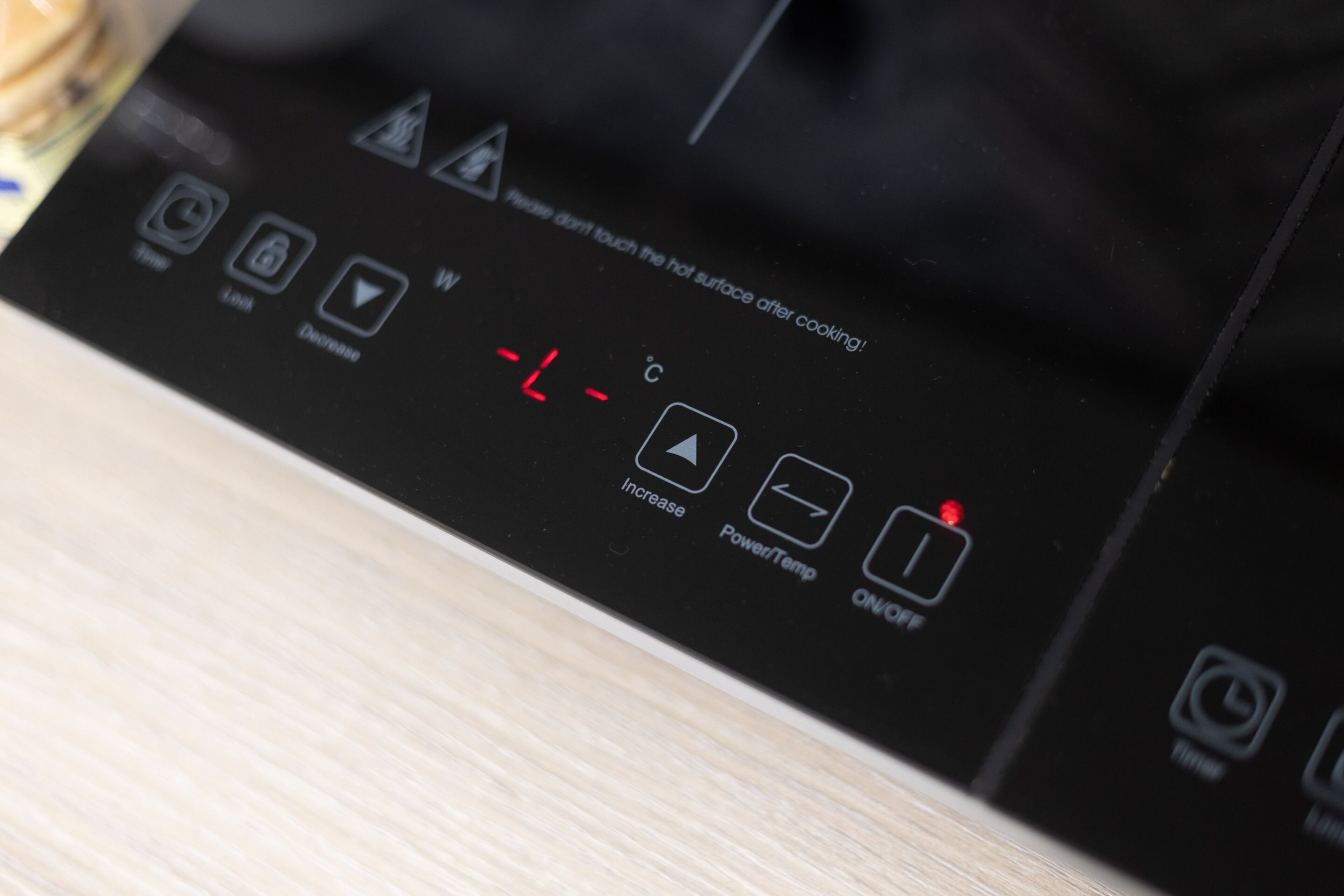 A black control panel with temperature settings and a warning about hot surface.