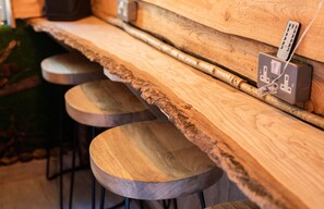A wooden bar with stools and a power outlet with a remote control. - James Place @ Pontmorlais (Merthyr Tydfil)