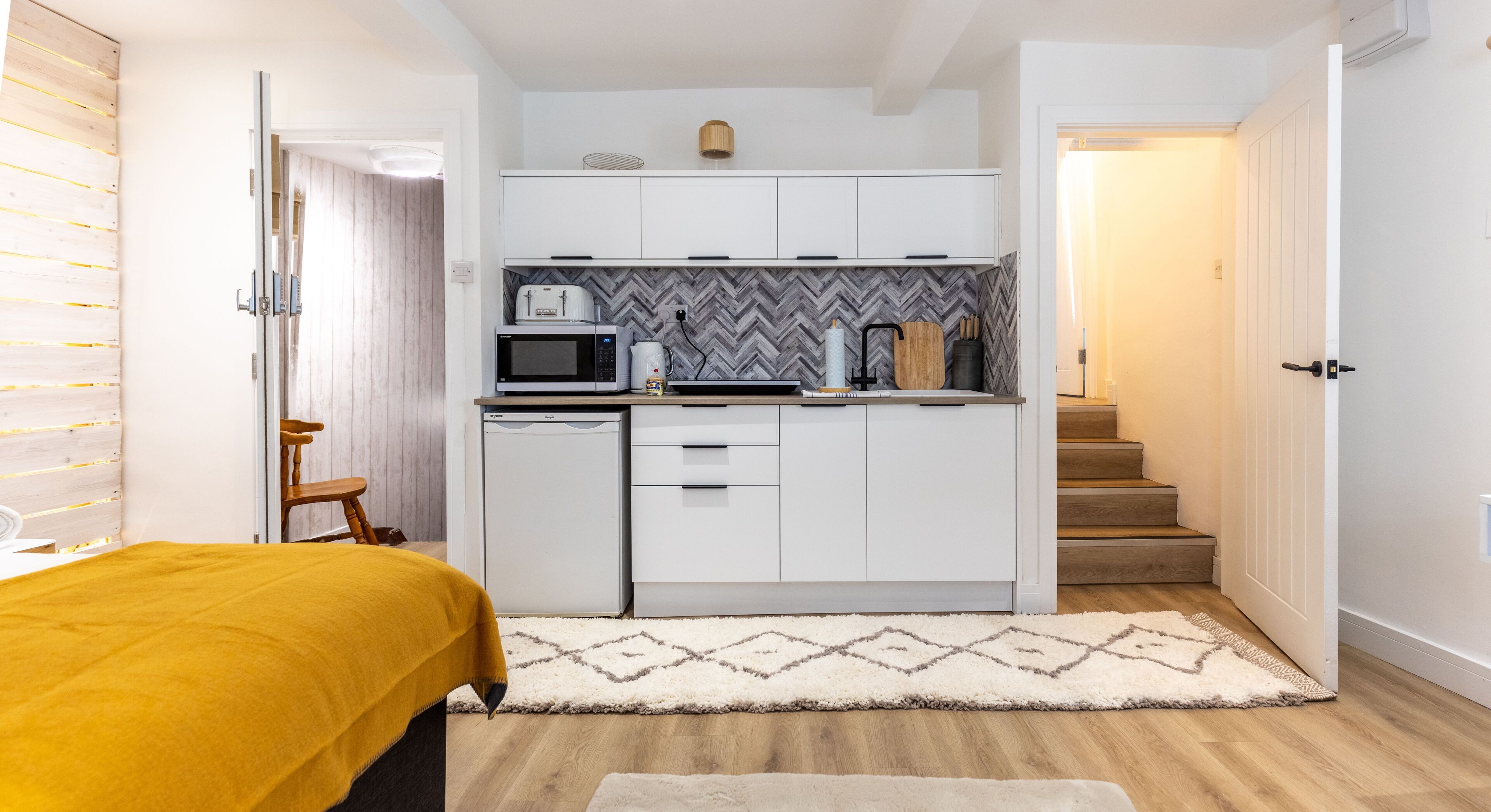 A compact kitchen with white cabinets, a microwave, and a coffee maker.