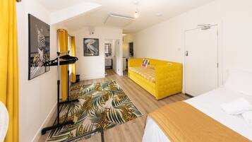 Quarto de hotel com cama, sofá, pequena escrivaninha e banheiro.
