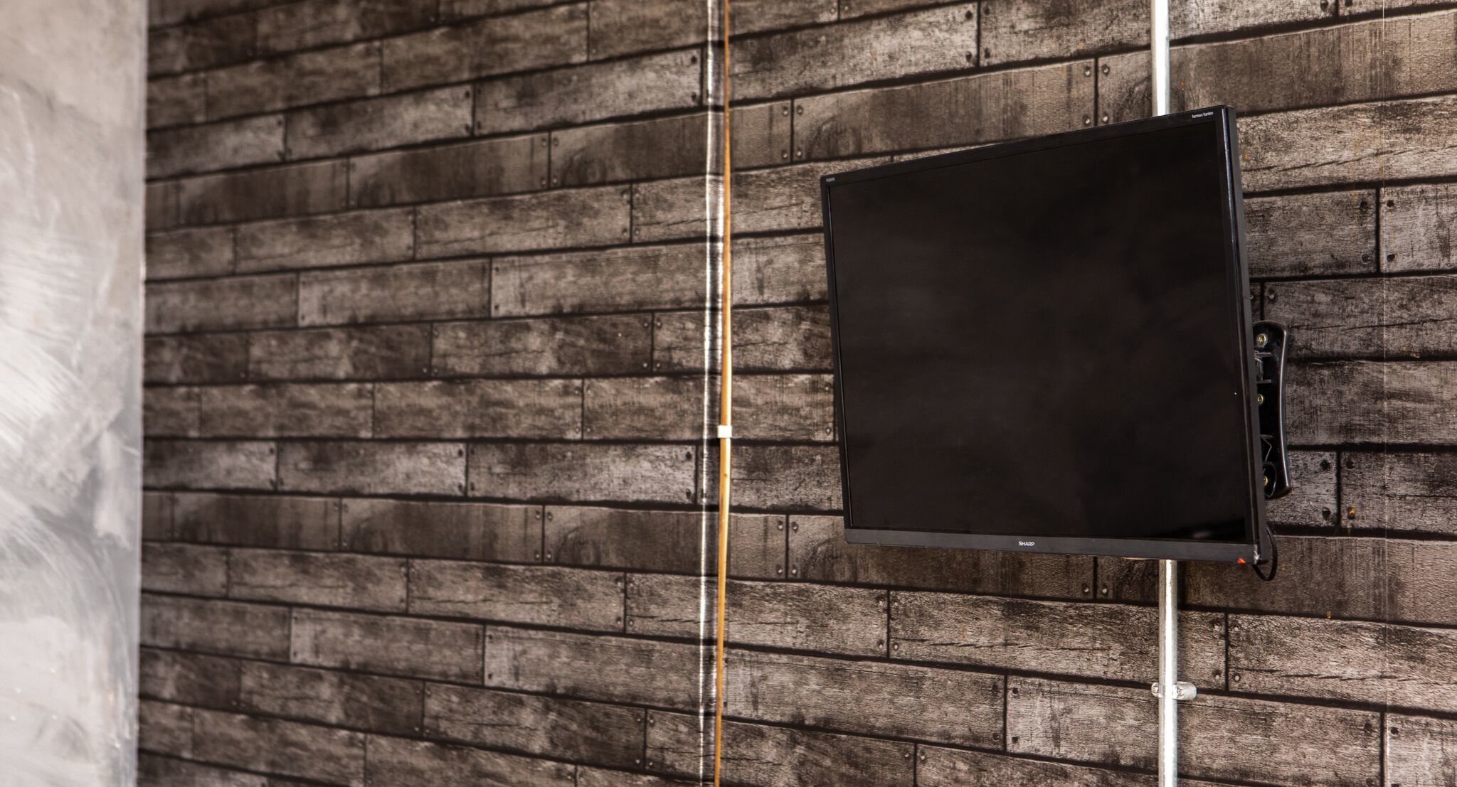 A black flat-screen TV mounted on a brick wall.