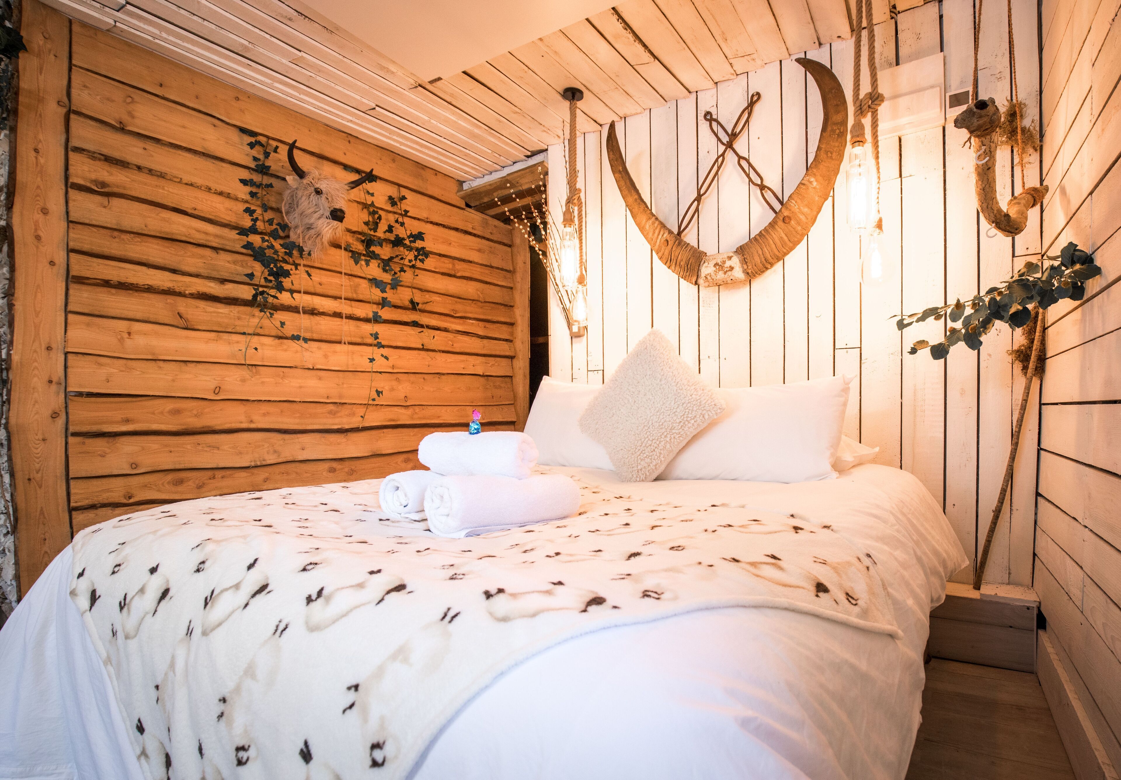 Ein gemütliches Zimmer mit einem Holzkopfteil, einem Bett mit gemustertem Überwurf und Wanddekorationen.