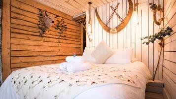 Ein gemütliches Zimmer mit einem Holzkopfteil, einem Bett mit gemustertem Überwurf und Wanddekorationen.