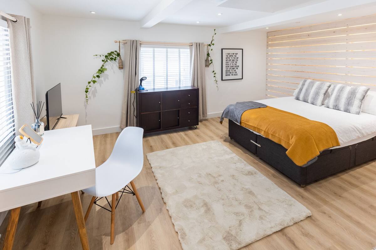 A modern bedroom with a bed, desk, chair, and a window with curtains.