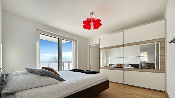 Camera da letto moderna con un letto grande, un armadio scorrevole e vista sull'esterno.