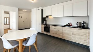 Una cucina moderna con pensili bianchi, un piano di lavoro nero e un tavolo da pranzo rotondo con sedie.