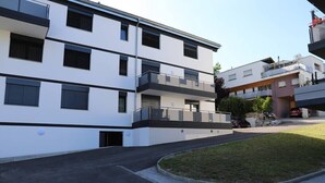 Un edificio residenziale a più piani con balconi, un'area di parcheggio e un piccolo prato.