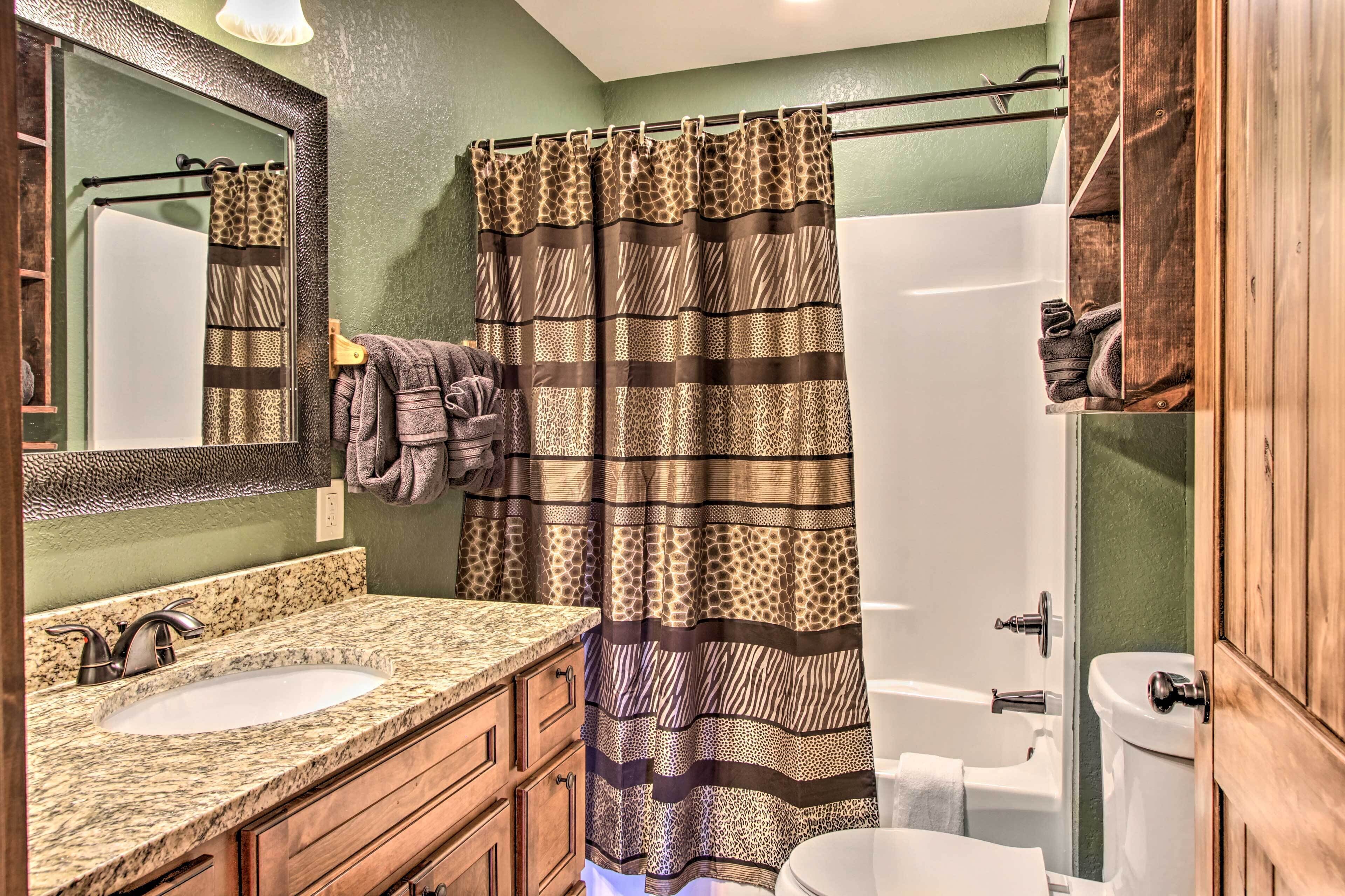 A bathroom with a shower curtain, a sink, a mirror, and a toilet.