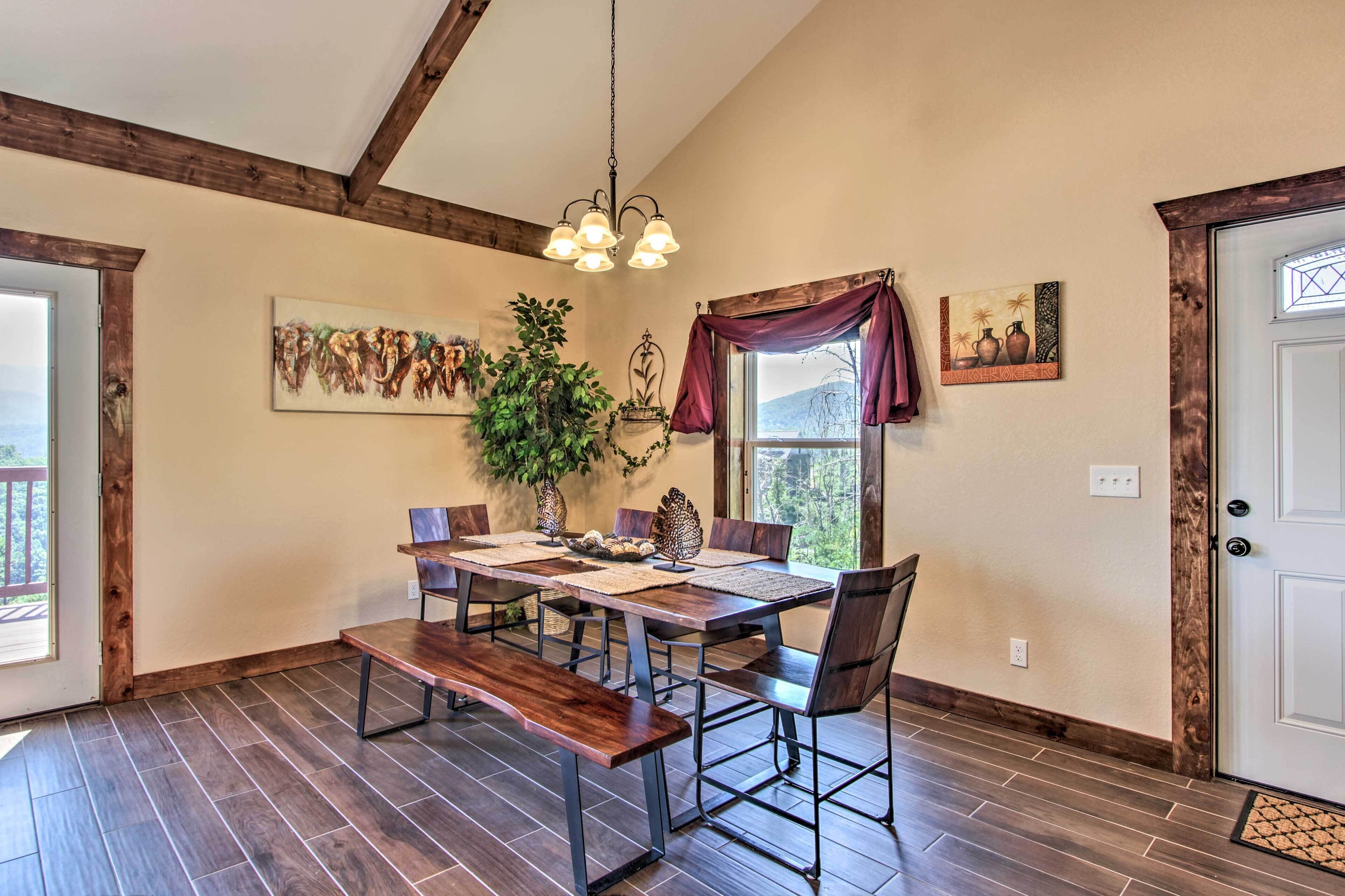 A dining area with a wooden table, benches, and a chandelier.
