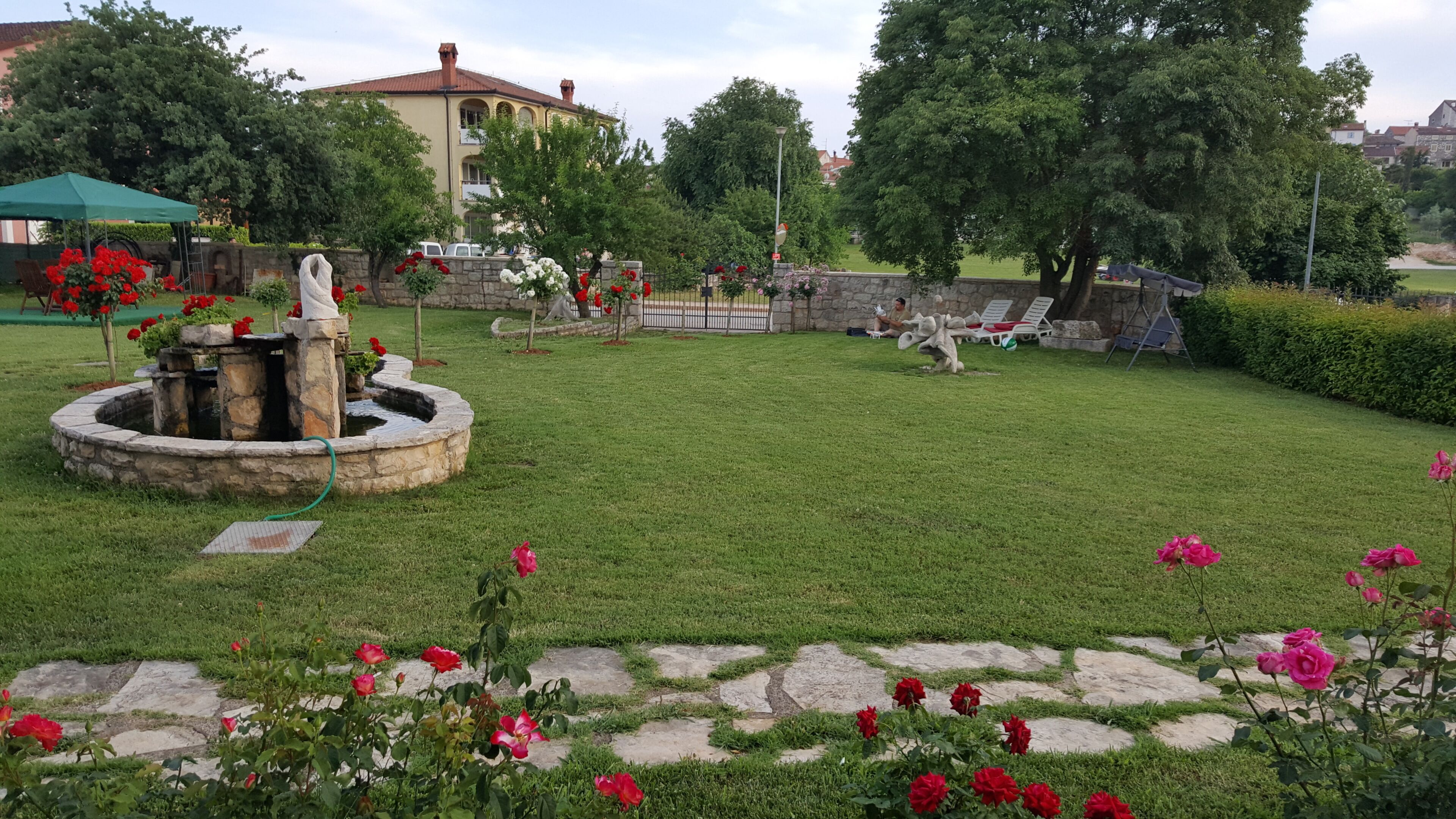 Un jardin bien entretenu, agrémenté d’une fontaine en pierre, d’un sentier dallé et d’une grande variété de fleurs.