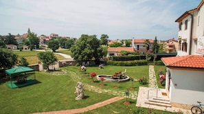 A courtyard with a fountain, greenery, and a building with a sign.