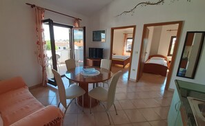 A room with a dining table, chairs, a sofa, a TV, a bed, and a bathroom. - Villa Linet (Funtana)
