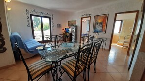 A dining area with a glass table, metal chairs, a blue cushioned bench, and a view through a window. - Villa Linet (Funtana)