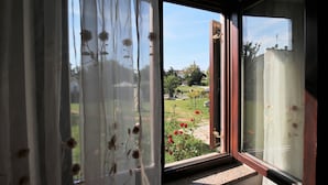 Una habitación con un ventanal grande, una puerta y vistas a un jardín con flores rojas.