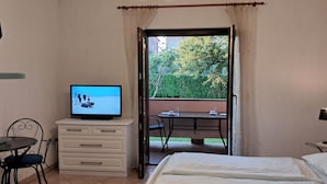 Habitación de hotel con cama, televisión, escritorio y vistas al exterior.