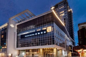 Un hôtel moderne, avec une façade en verre remarquable et une enseigne indiquant qu’il s’agit de l’hôtel Hilton.
