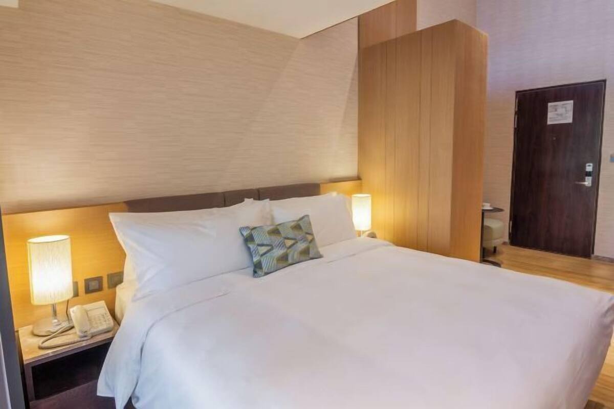 Een hotelkamer met een groot bed, twee bedlampjes, een telefoon en een houten paneelwand.