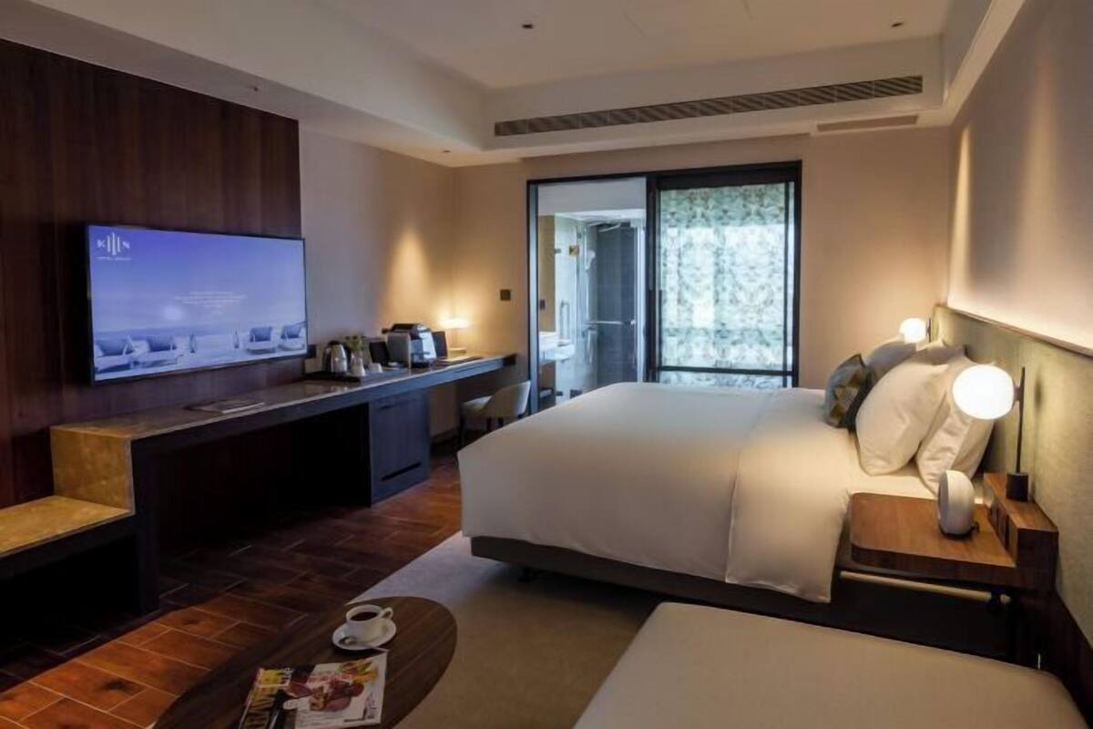Een moderne hotelkamer met een groot bed, een bureau, een televisie en een balkon met uitzicht.