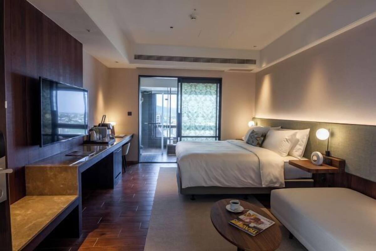 Een hotelkamer met een bed, een bureau met een televisie, een salontafel en uitzicht op het omliggende landschap.