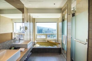 A modern bathroom with a bathtub, a large window, and a view of the city. - Kilin Hotel JiaoXi (Jiaoxi)