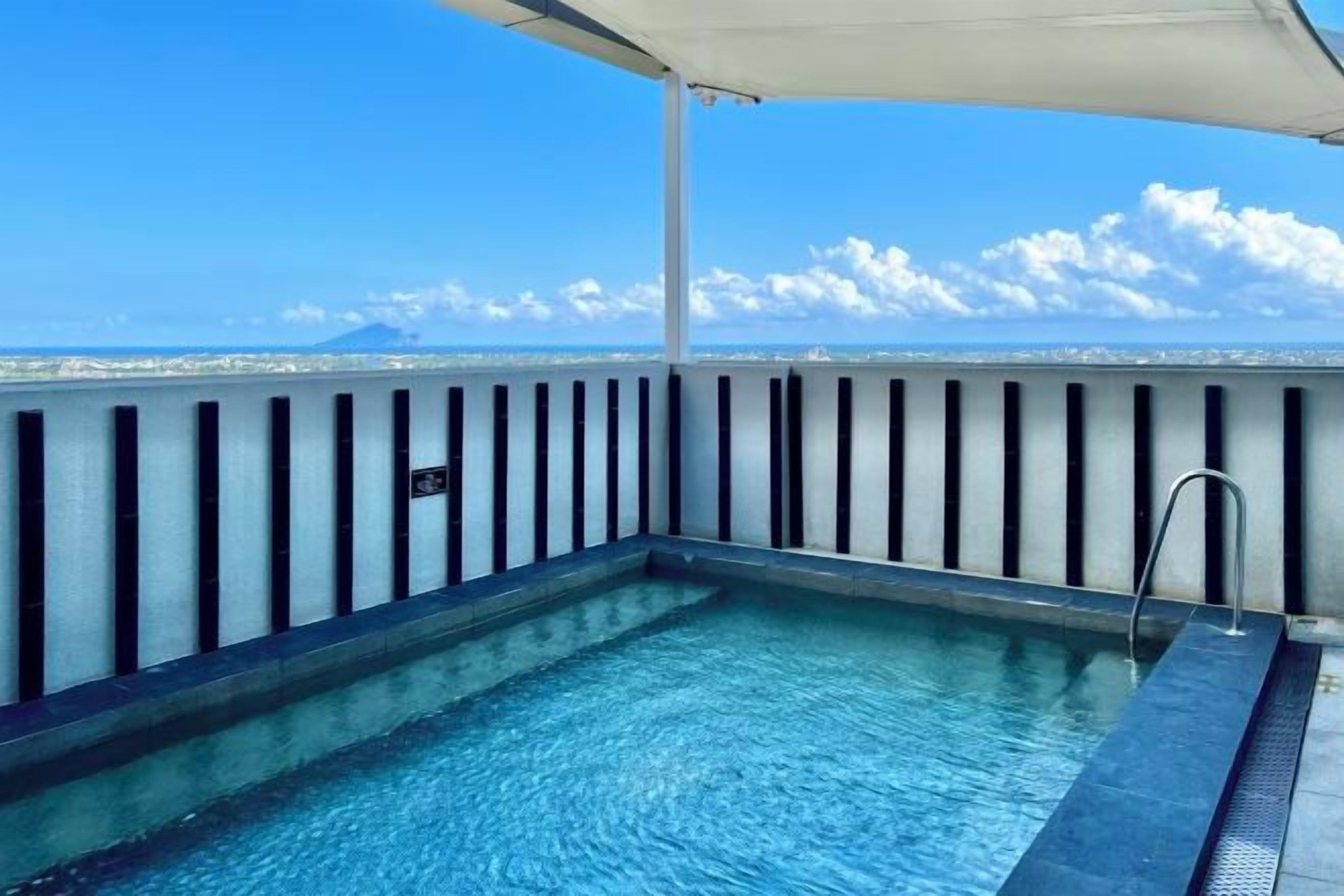 A rooftop pool with a clear view of the city skyline and clouds.