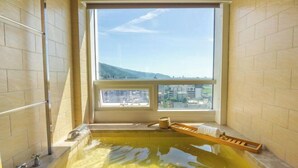 Una vasca da bagno con vista sulla città attraverso un'ampia finestra.