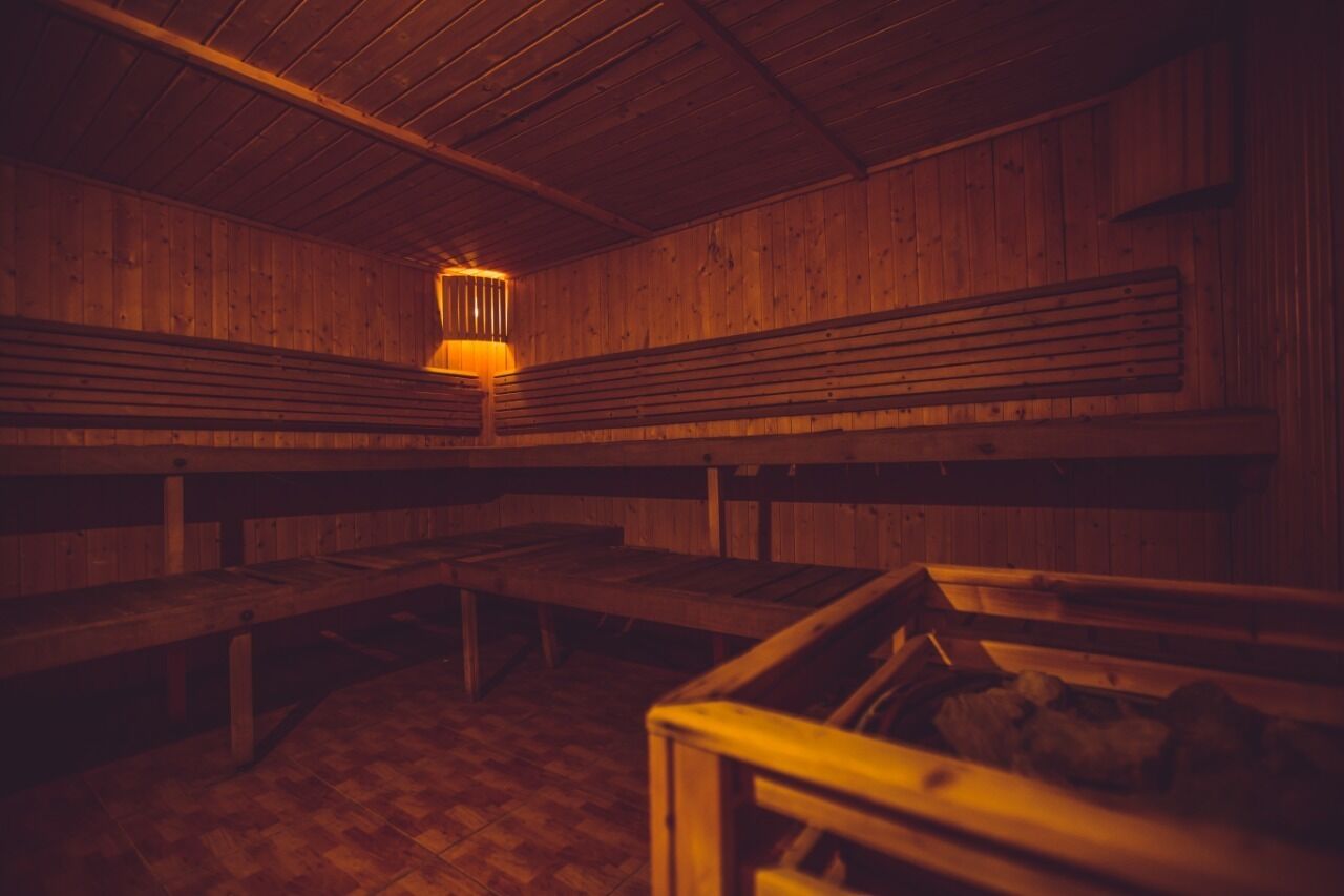 A sauna with wooden benches and a central light fixture.