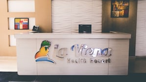 Un comptoir d’accueil au La Riviera Health Resort, doté d’un design moderne, d’un téléphone et d’un petit porte-cartes.