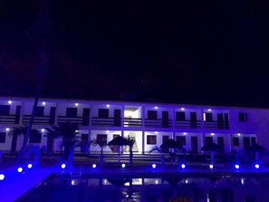 Un edificio de varios pisos con una piscina delantera.