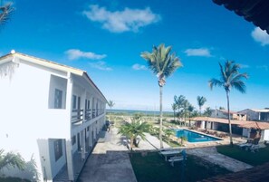 Un edificio con piscina, palmeras y un cielo azul despejado.
