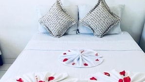 A neatly made bed with white sheets and two decorative pillows.