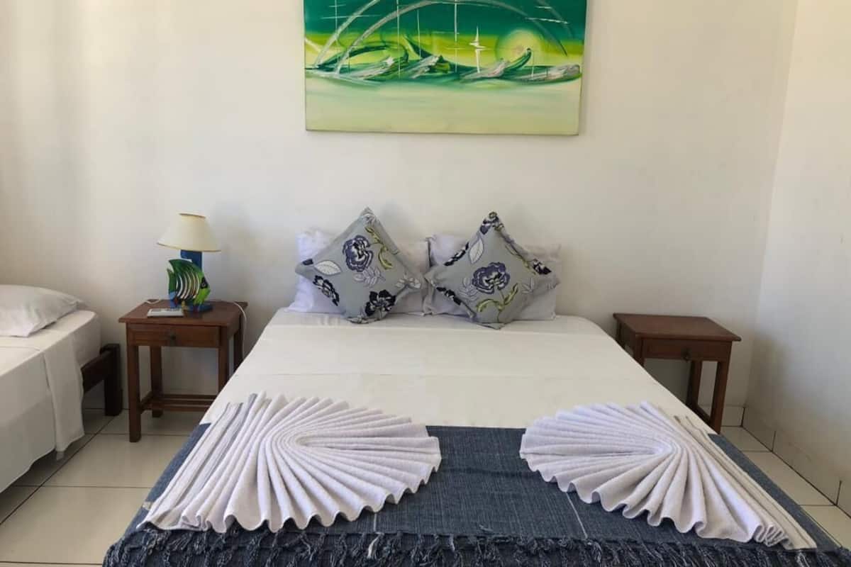 Ein ordentlich eingerichtetes Hotelzimmer mit einem Bett, zwei Nachttischen, einer Lampe und einem Bild an der Wand.