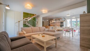 Una sala de estar moderna con sofá, mesa de centro y una escalera que lleva a una cocina.