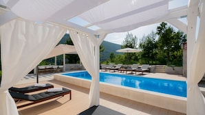 Zona junto a la piscina con vista despejada, tumbonas y una mesa con sillas.